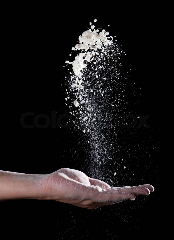 Chef hand clap with splash of white flour and black background, stock photo