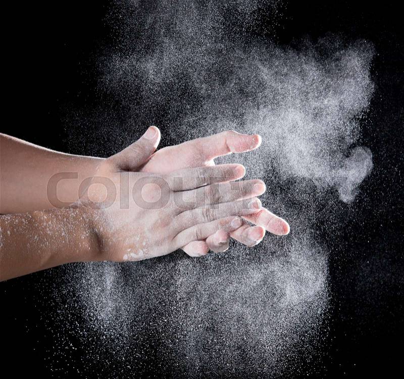 Chef hand clap with splash of white flour and black background, stock photo