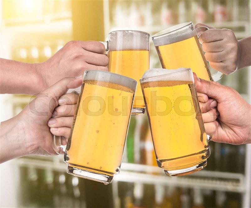 Leisure and drinks concept , male hands clinking beer mugs at bar or pub, stock photo