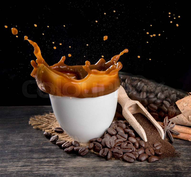 Coffee splash with coffee beans on table wood over dark background, stock photo
