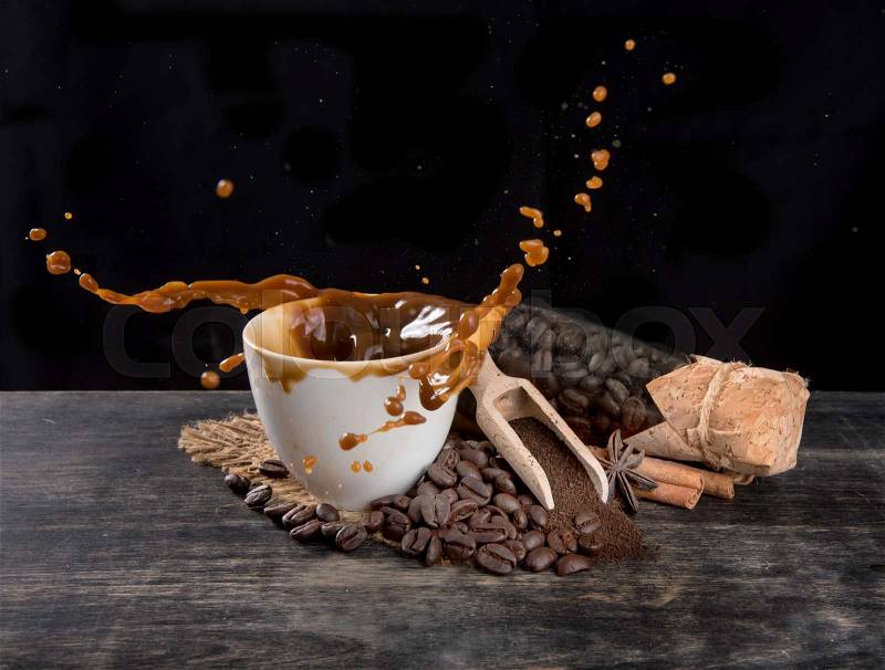 Coffee splash with coffee beans on table wood over dark background, stock photo
