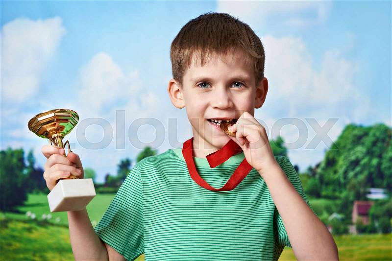 Boy sportsman winner with cup and medal on nature background, stock photo
