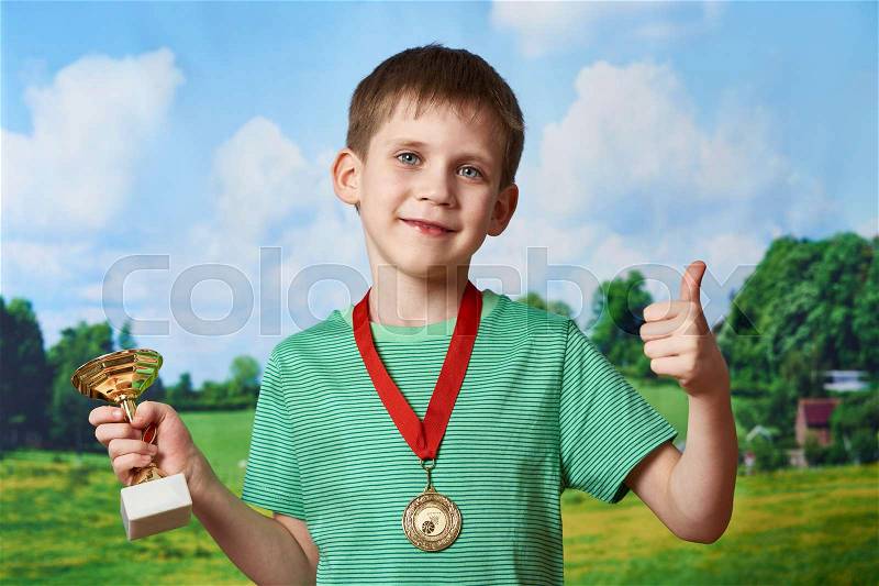 Boy sportsman winner with cup and medal on nature background, stock photo