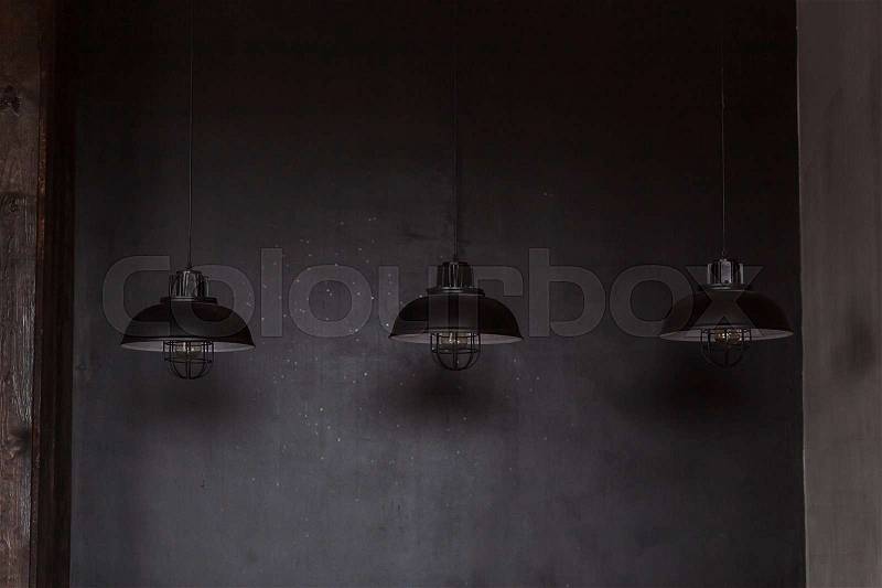 Loft industrial wire pendant lamps against rough wall, stock photo