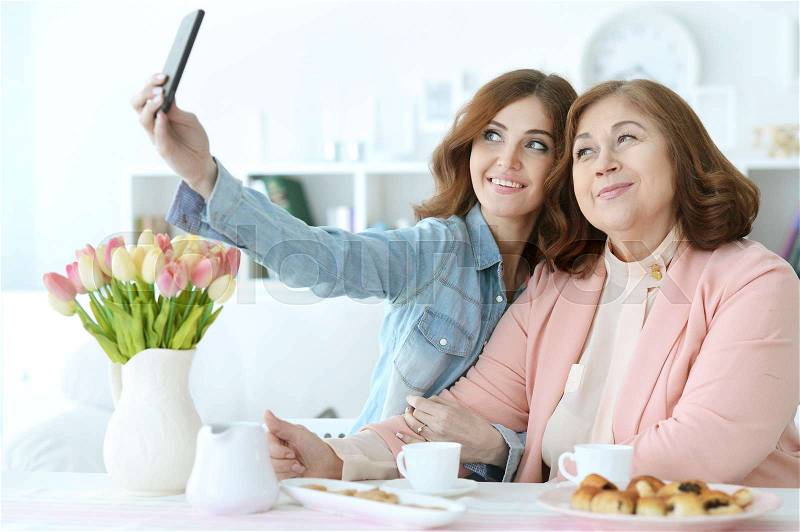 Adult daughter teaches an elderly mother to use a mobile phone, stock photo