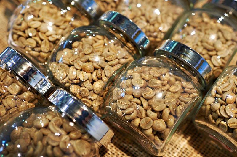 Unroasted or light roasted coffee in glass jars, stock photo