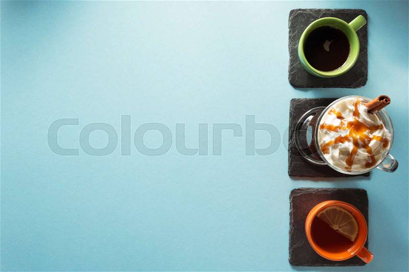 Cup of ice cream coffee, tea and cacao at blue paper background, stock photo