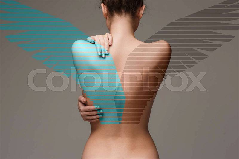 The back of attractive woman with angel wings on gray studio background, stock photo
