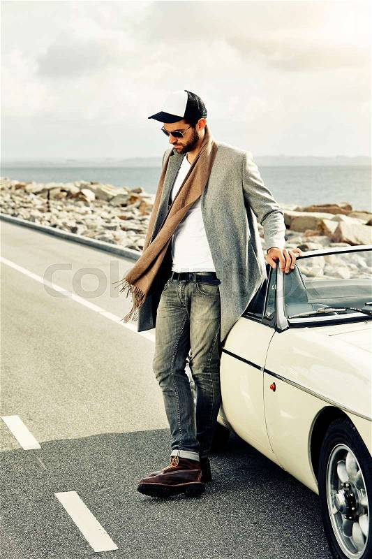 Dude with cool car on road, looking down, stock photo