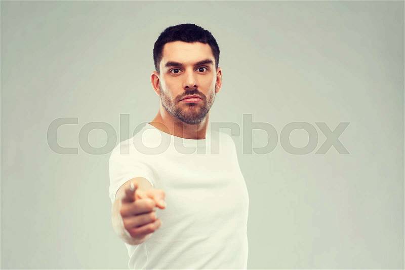 Emotion, gesture and people concept - angry man pointing finger to you over gray background, stock photo