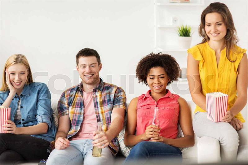 Friendship, junk food, people and entertainment concept - happy friends with popcorn and beer watching tv at home, stock photo