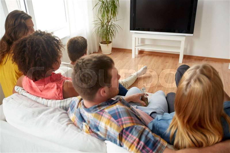 Friendship, communication, people and entertainment concept - happy friends drinking beer or cider and watching tv at home, stock photo