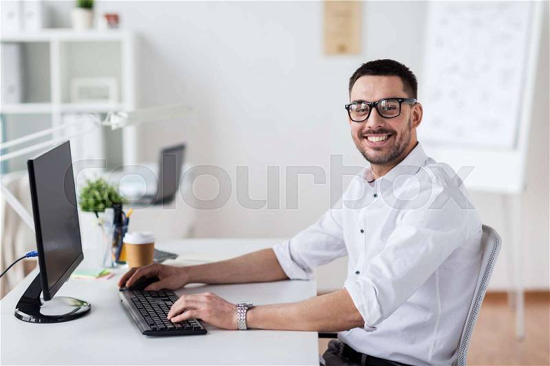 Business, people and technology concept - happy businessman typing on computer keyboard at office, stock photo