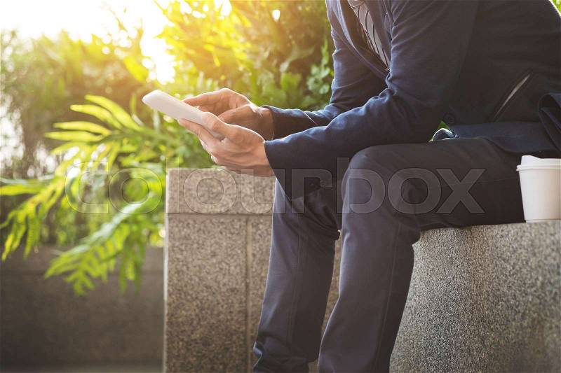 Asian Indian businessman using tablet pc outdoors, golden sunlight background, stock photo