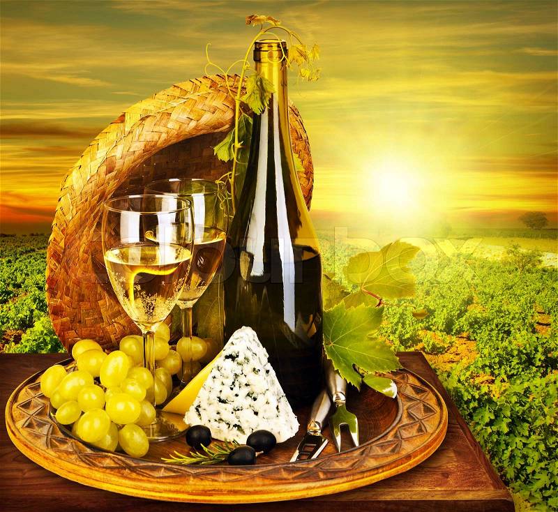 Wine and cheese romantic dinner outdoor, table for two with vineyard view, fresh grapes and wineglass at restaurant, warm autumn sunset, grape field landscape at harvest, food still life, stock photo