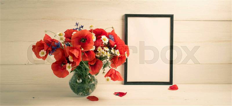 Red poppies bouquet in round vase and motivational frame for text on background of white wooden planks in scandinavian style, stock photo