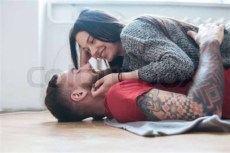 Man and woman lying together on the wooden floor, stock photo