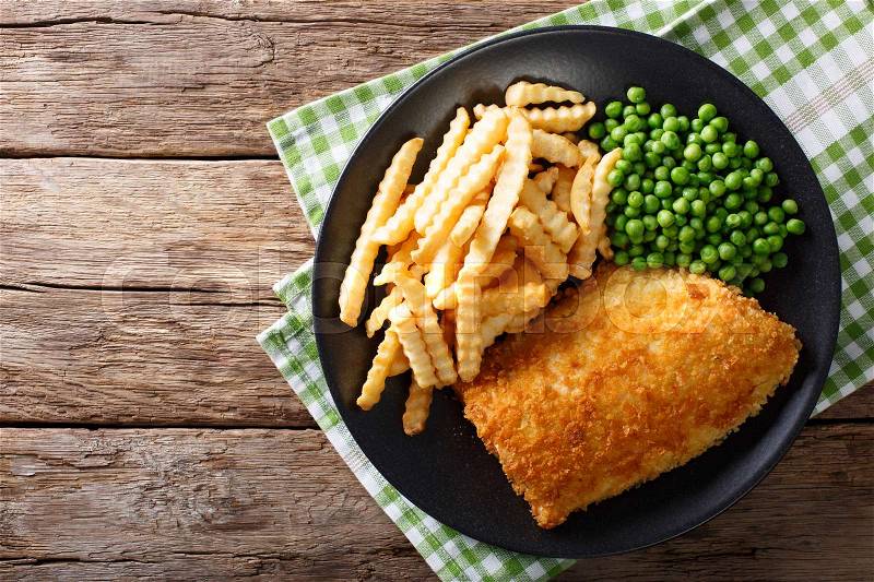 Traditional British food: Fish and chips with green peas close-up on a plate on a table. horizontal view from above , stock photo