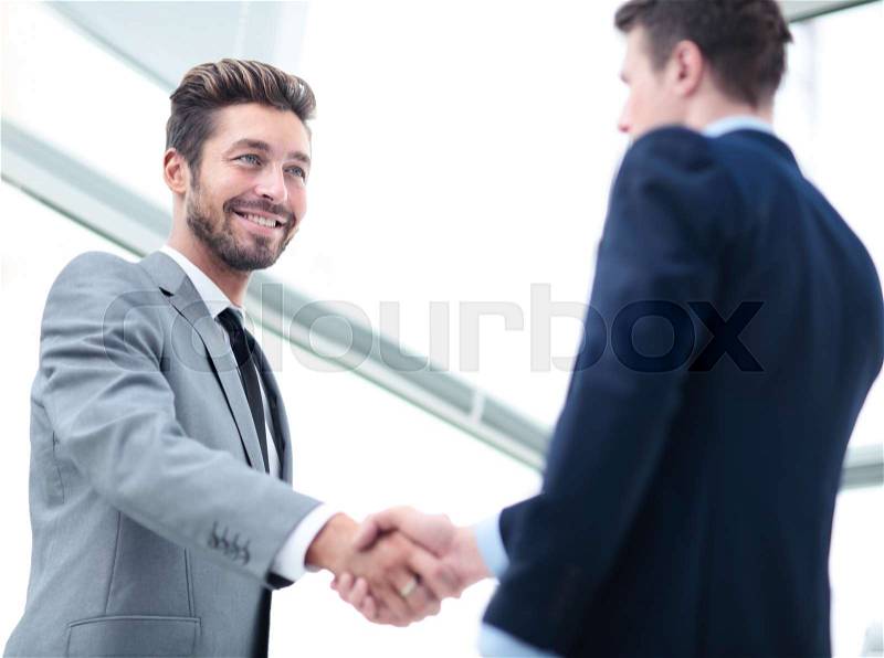 Two business people shaking hands and looking at each other with smile, stock photo