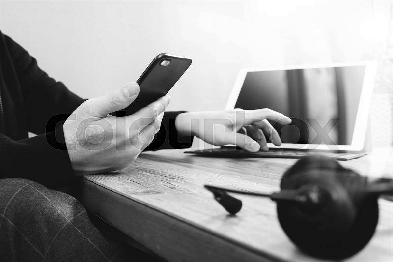 Man hand using VOIP headset with digital tablet computer docking keyboard,smart phone,concept communication, it support, call center and customer service help desk on wooden table,black and white, stock photo