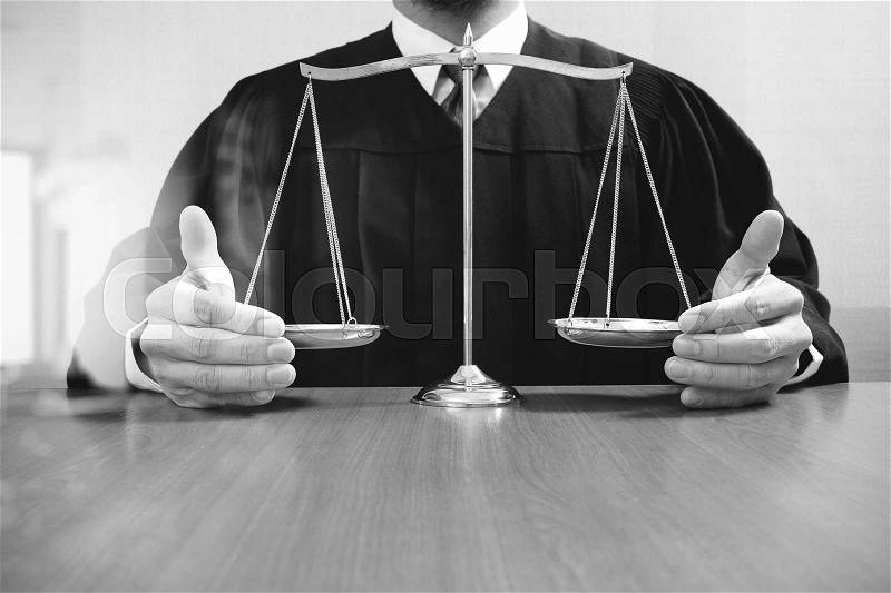 Justice and law concept.Male judge in a courtroom with the balance scaleon wood table,black and white, stock photo