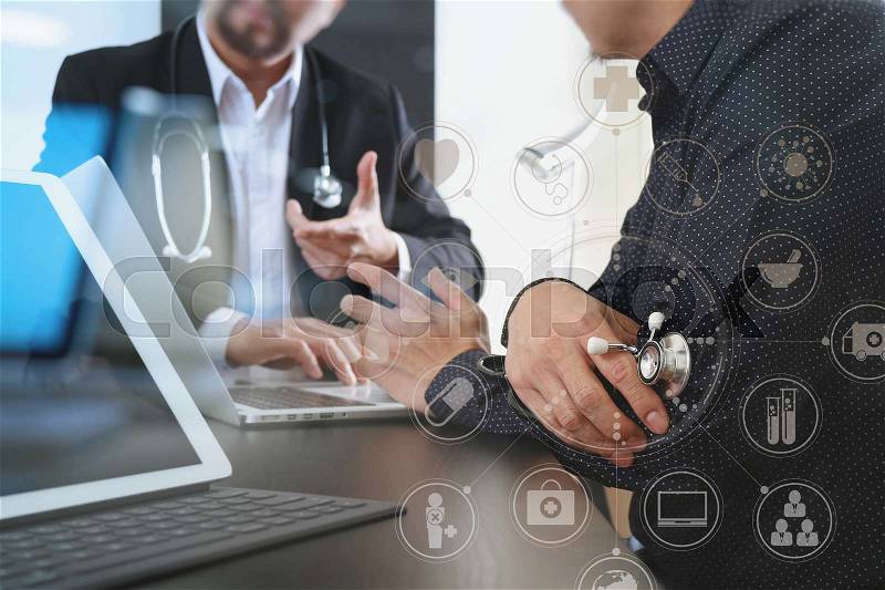 Medical co working concept,Doctor working with digital tablet and laptop computer formeeting his team in modern office at hospital with virtual interface graphic icons network diagram, stock photo