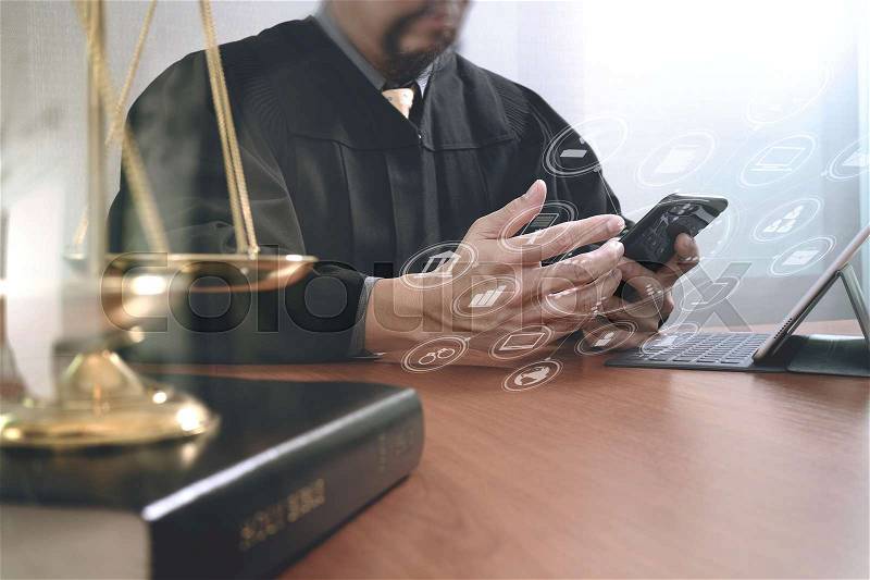 Justice and law concept.Male judge in a courtroom with the gavel and working with smart phone and brass scale on wood table with virtual interface graphic icons diagram, stock photo