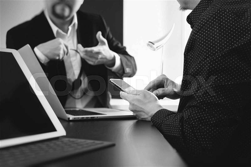 Co working team meeting concept,businessman using smart phone and digital tablet and laptop computer in modern office,black and white, stock photo