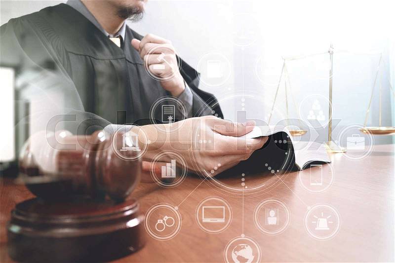 Justice and law concept.Male judge in a courtroom with the gavel,opening holy book and digital tablet computer with brass scale on wood table with virtual interface graphic icons diagram , stock photo