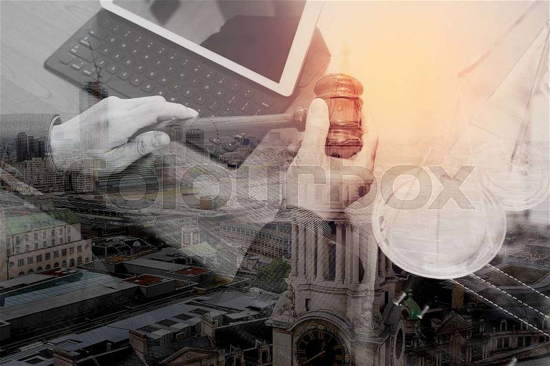 Double exposure of justice and law concept.Male judge in a courtroom with the gavel,working with smart phone,digital tablet computer docking keyboard,brass scale,on wood table,London architecture city, stock photo