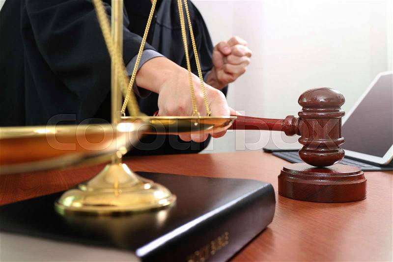 Justice and law concept.Male judge in a courtroom with the gavel,working with smart phone and digital tablet computer with brass scale on wood table , stock photo