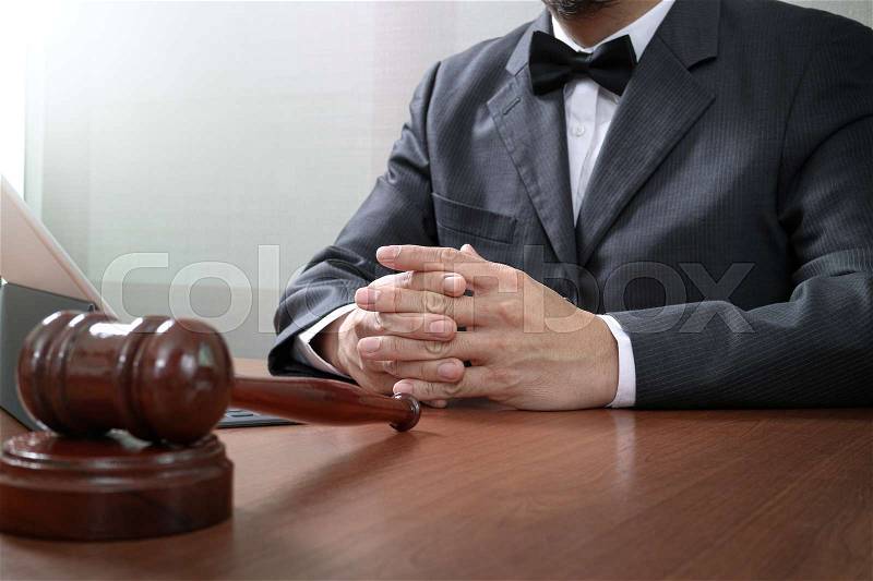 Justice and law concept.Male lawyer in office with the gavel,working with smart phone,digital tablet computer docking keyboard,brass scale,on wood table, stock photo