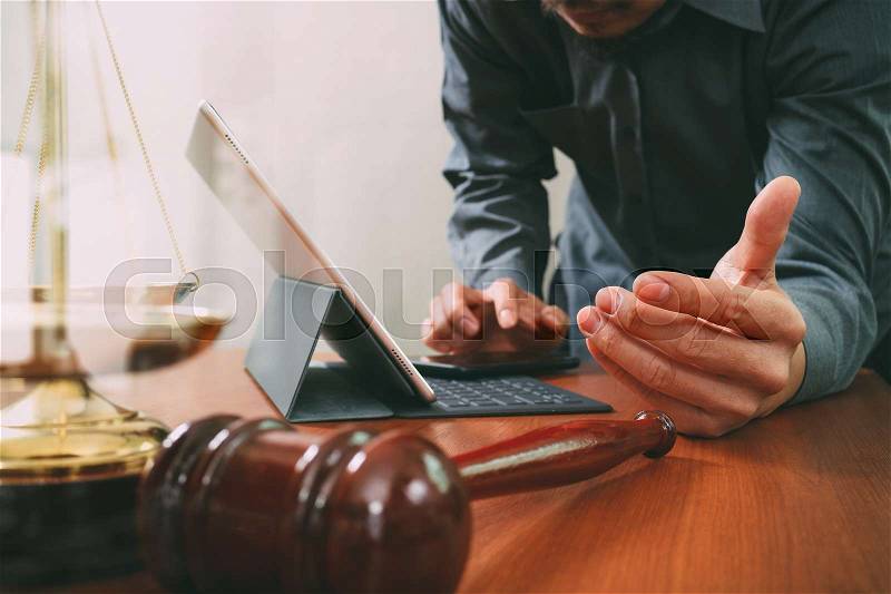 Justice and law concept.Male lawyer in office with the gavel,working with smart phone and digital tablet computer and brass scale on wood table, stock photo