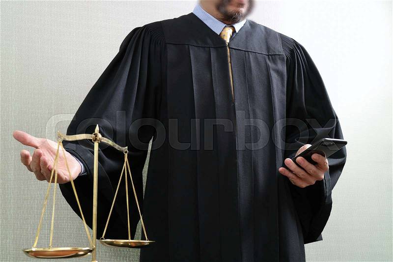 Justice and law concept.Male judge in a courtroom with the balance scale and using smart phone, stock photo