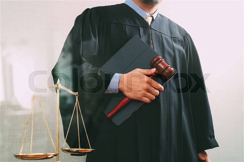 Justice and law concept.Male judge in a courtroom with the gavel and balance scale and holy book and digital tablet computer, stock photo