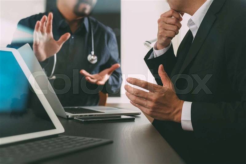 Medical co working concept,Doctor working with smart phone and digital tablet and laptop computer to meeting his team in modern office at hospital, stock photo