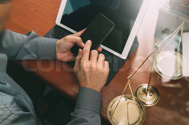 Justice and law concept.Male lawyer in office with the gavel,working with smart phone,digital tablet computer docking keyboard,brass scale,on wood table,filter effect, stock photo