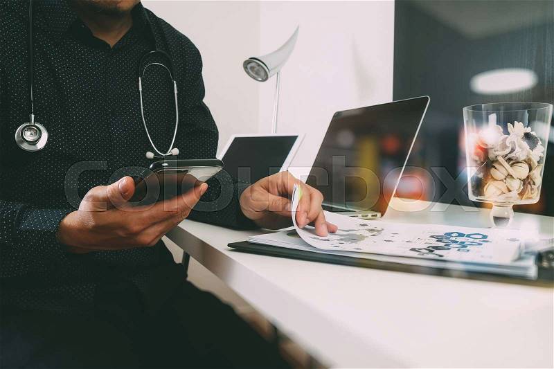 Smart medical doctor working with smart phone and digital tablet and laptop computer and stethoscope on wood desk in modern office, stock photo