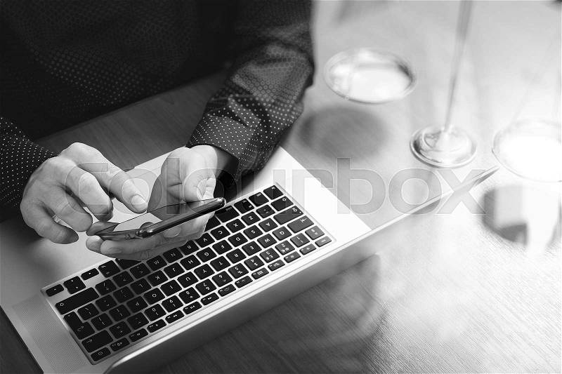 Justice and law concept.Male lawyer in office with the gavel,working with smart phone,digital tablet computer docking keyboard,brass scale,on wood table,black and white, stock photo
