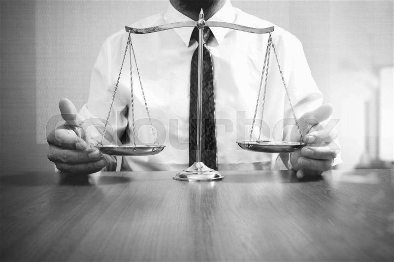Justice and law concept.Male lawyer in the office with brass scale on wooden table,black and white, stock photo