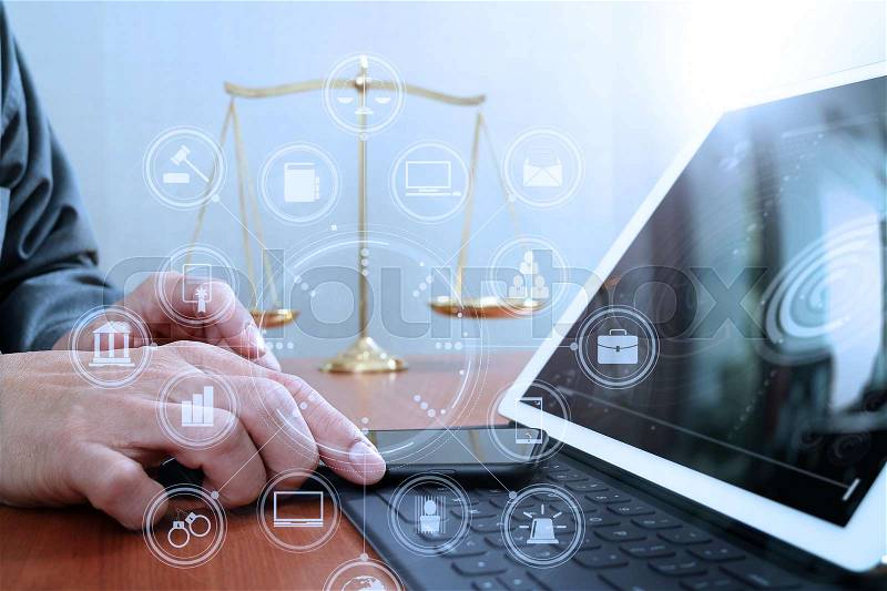 Justice and law concept.Male lawyer in office with the balance brass scale,hand working with smart phone and digital tablet computer on wooden desk,virtual graphic icons screen diagram, stock photo
