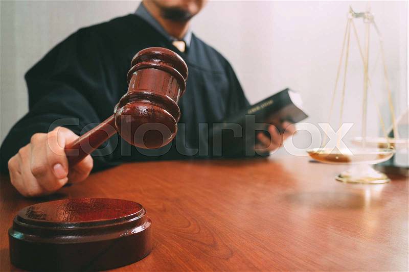 Justice and law concept.Male judge in a courtroom with the gavel and working with smart phone and brass scale on wood table, stock photo