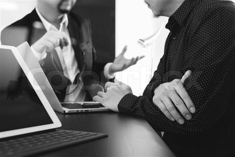 Co working team meeting concept,Man using VOIP headset with digital tablet and latop computer and smart phone in modern office,black and white , stock photo