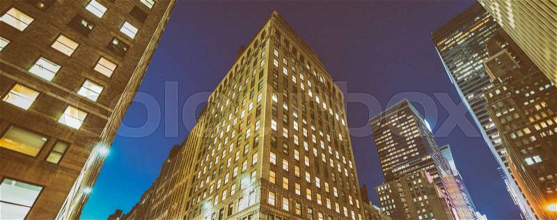 Night view of New York buildings from street level, stock photo