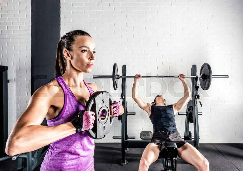 Young sportspeople training in gym with barbell and weight plates, stock photo