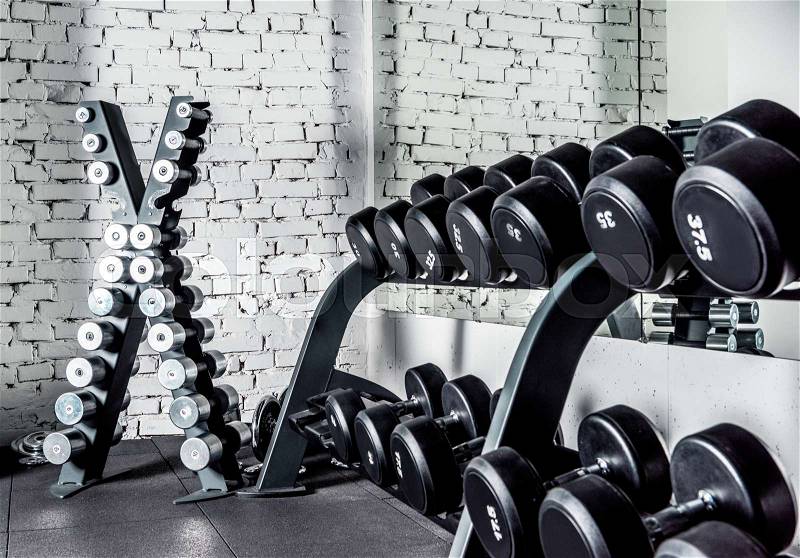 Well-ordered weight training equipment in modern sports club, stock photo