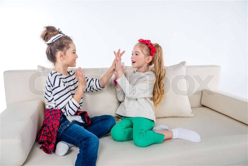 Side view of cheerful girls playing patty-cake game, stock photo