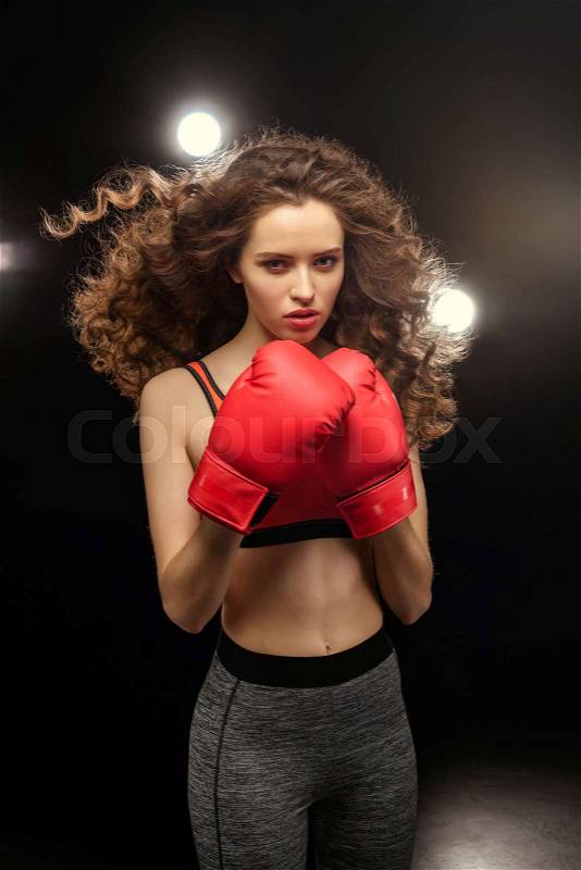 Beautiful young woman boxer in sportswear posing on dark, stock photo