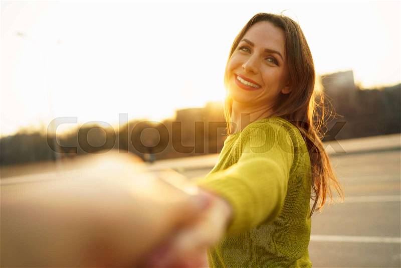 Follow me - happy young woman pulling guy\'s hand - hand in hand walking on a bright sunny day - concept of carefree modern life, stock photo