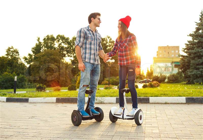 Young couple riding hoverboard - electrical scooter, personal eco transport, gyro scooter, smart balance wheel. New modern technologies, stock photo